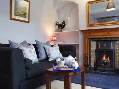 a living room with a couch and a fireplace at Ardchoille Cottage in Fortingall