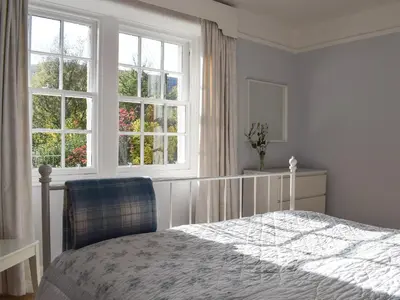 a bedroom with a bed and two windows at Ardchoille Cottage in Fortingall