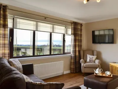 a living room with a couch and a large window at Hillview in Beith