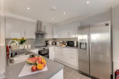 a kitchen with stainless steel appliances and a cutting board with fruit at Beach Houses with Hot Tubs in Glencoe