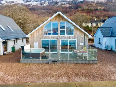 a house with a screened in porch with a table at Beach Houses with Hot Tubs in Glencoe