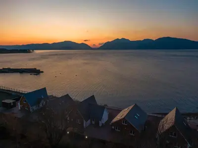 a sunset over the water with houses and mountains at Beach Houses with Hot Tubs in Glencoe