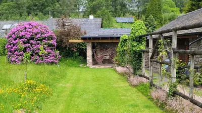 a garden with pink flowers and a wooden fence at Loch Lomond shore Boat House in Balmaha