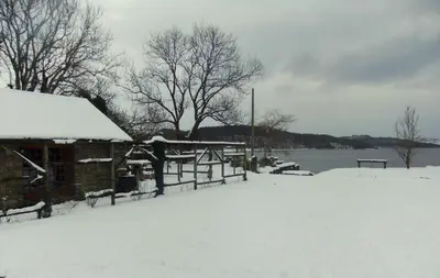 a cabin covered in snow next to a lake at Loch Lomond shore Boat House in Balmaha