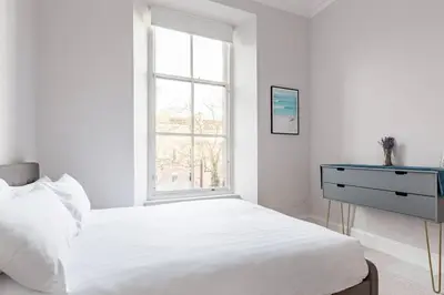a white bedroom with a bed and a window at Incredible contemporary flat in heart of west end in Glasgow