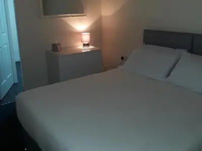 a bedroom with a white bed with a lamp on a table at Stonefield Rooms in High Blantyre