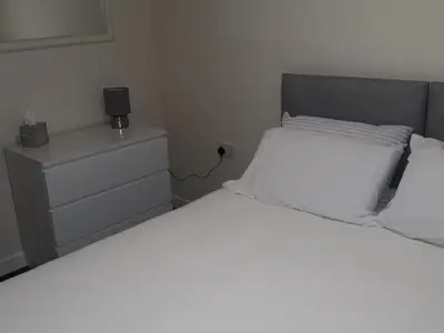 a bedroom with a large white bed and a dresser at Stonefield Rooms in High Blantyre