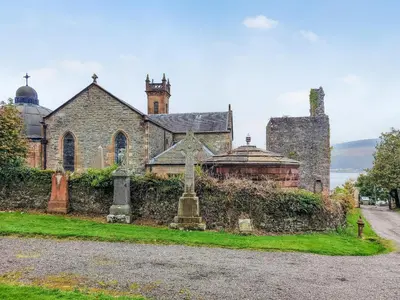 an old stone church with a cemetery in front of it at Firwood Apartment in Kilmun