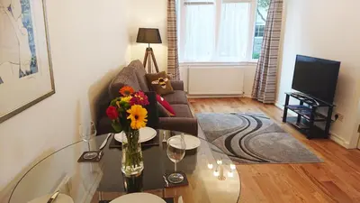 a living room with a vase of flowers on a glass table at Violet Bank Apartment West End. in Edinburgh