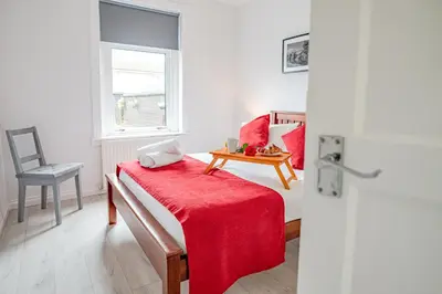 a room with a bed with a red blanket and a table at Stirling Mercury Apartment - Scotland Holiday Let in Stirling