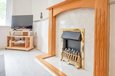 a living room with a fireplace and a television at Stirling Mercury Apartment - Scotland Holiday Let in Stirling