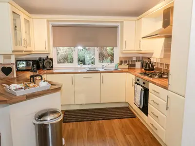 a kitchen with white cabinets and a sink and a window at The Wee Lodge in Glendevon