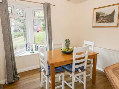 a dining room with a wooden table and chairs and a window at The Wee Lodge in Glendevon