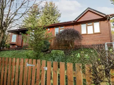 a wooden house with a fence in front of it at The Wee Lodge in Glendevon