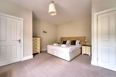 a bedroom with a white bed and two dressers at JOIVY Bright 1 bed flat, close to Princess Street in Edinburgh