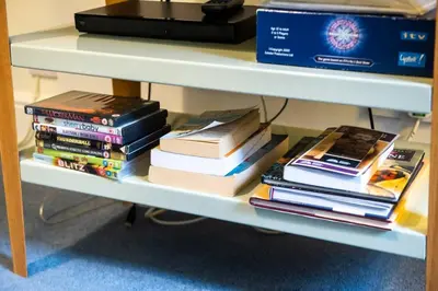 a pile of books sitting on a shelf at JOIVY Stylish Home in New Town in Edinburgh