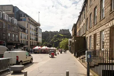 a city street with buildings and a castle in the background at JOIVY Stylish Home in New Town in Edinburgh