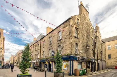 an old brick building on a city street with red flags at JOIVY Stylish Home in New Town in Edinburgh