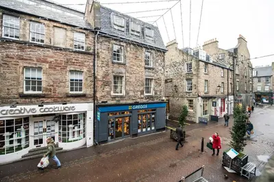 a group of people walking down a street with buildings at JOIVY Charming Apt close to City Centre in Edinburgh