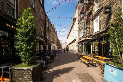 an empty street with tables and benches in a city at JOIVY Amazing Location! Lovely Rose St Apt in New Town in Edinburgh