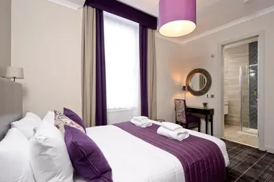a bedroom with a large bed with purple and white pillows at Destiny Scotland Charlotte Square Apartments in Edinburgh