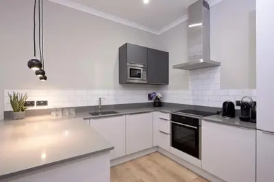 a kitchen with white cabinets and a sink and a microwave at Destiny Scotland Charlotte Square Apartments in Edinburgh