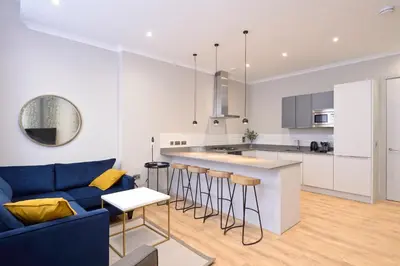 a kitchen and living room with a blue couch at Destiny Scotland Charlotte Square Apartments in Edinburgh