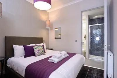 a bedroom with a large white bed with purple sheets at Destiny Scotland Charlotte Square Apartments in Edinburgh