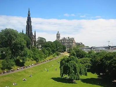 a park with people sitting on the grass in a city at GuestReady - Stylish 2BR in Heart of Tollcross in Edinburgh