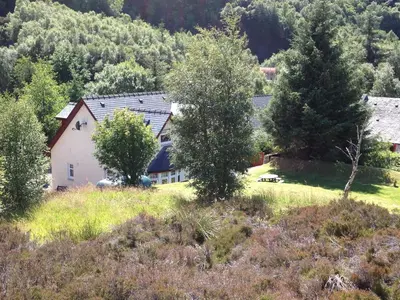 a house in the middle of a field with trees at Stormfront Luxury Hideaway Glencoe Ballachulish Highlands Near Fortwilliam in Glencoe