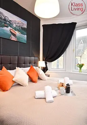 a bedroom with a large bed with orange and white pillows at Whifflet Apartment by Klass Living Coatbridge in Coatbridge