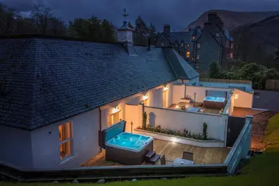 a house with a hot tub on a deck at night at Glencoe House in Glencoe