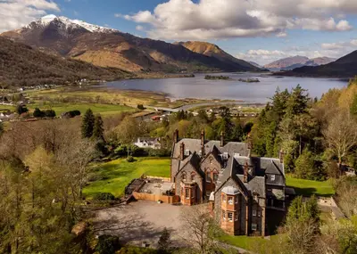 an aerial view of a mansion with a lake and mountains at Glencoe House in Glencoe