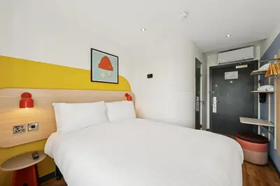 a bedroom with a white bed and a yellow wall at Garner Hotel Edinburgh - Haymarket by IHG in Edinburgh