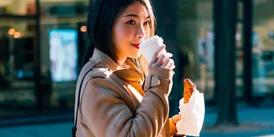 a woman in a leather jacket eating a piece of food at Garner Hotel Edinburgh - Haymarket by IHG in Edinburgh