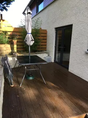 a table with an umbrella on a wooden deck at 1 Balnakeil, Kirk Road in Oban