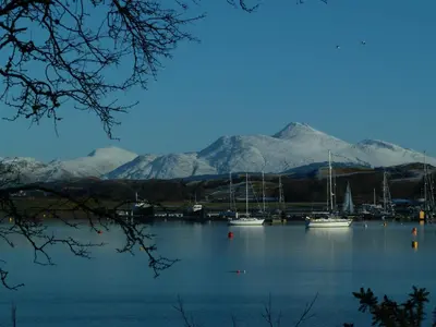 a group of boats on a lake with mountains in the background at 1 Balnakeil, Kirk Road in Oban