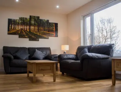 a living room with two leather couches and a window at 1 Balnakeil, Kirk Road in Oban