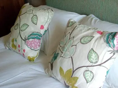 two pillows on top of a bed with white sheets at The Colonsay Hotel in Isle of Colonsay