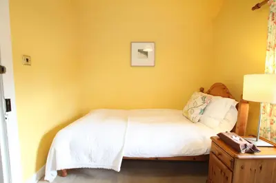 a bedroom with a bed and a yellow wall at The Colonsay Hotel in Isle of Colonsay