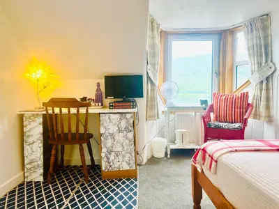 a bedroom with a desk and a bed and a chair at Rowantreebank Bed and Breakfast in Arrochar