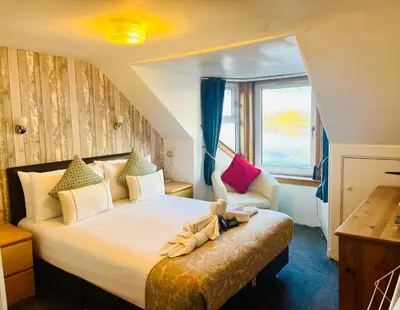 a bedroom with a large bed and a window at Rowantreebank Bed and Breakfast in Arrochar