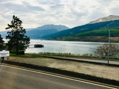 a road next to a body of water with mountains at Rowantreebank Bed and Breakfast in Arrochar