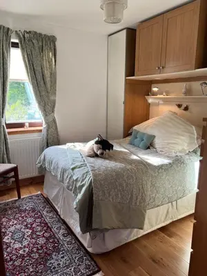 a cat sitting on a bed in a bedroom at Shenavallie Farm in Benderloch