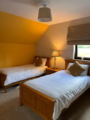 two beds in a room with yellow walls at Shenavallie Farm in Benderloch