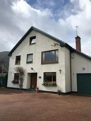 a white house with windows and a garage at The Woolly Rock in North Ballachulish