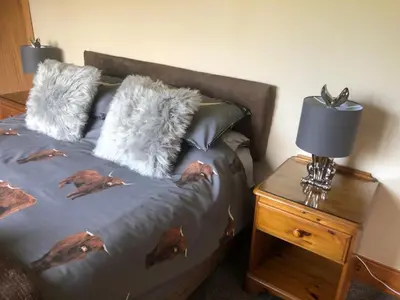 a bed with furry pillows and a table with a lamp at The Woolly Rock in North Ballachulish