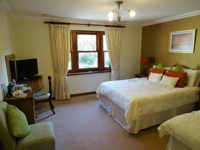 a hotel room with two beds and a window at Ardno House B & B in Glencoe