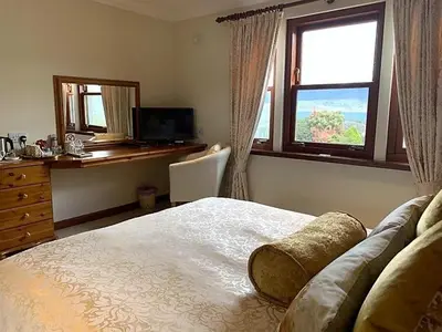 a bedroom with a bed and a desk and a window at Ardno House B & B in Glencoe
