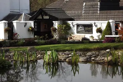 a house with a pond in front of it at Glazert Country House Hotel in Lennoxtown